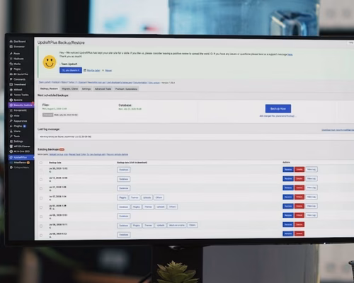 Ein Desktop-Monitor in einem Wiener Büro zeigt das WordPress-Backend-Dashboard mit Statusmeldungen zu verfügbaren Plugin-Updates, Sicherheitskontrollen und dem Backup-Status.