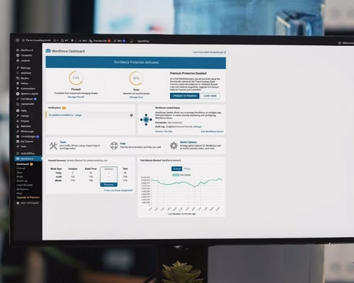 Nahaufnahme eines Monitors in einem modernen Büro, auf dem das Wordfence-Sicherheits-Dashboard einer WordPress-Website mit aktiver Firewall und Scan-Status angezeigt wird.