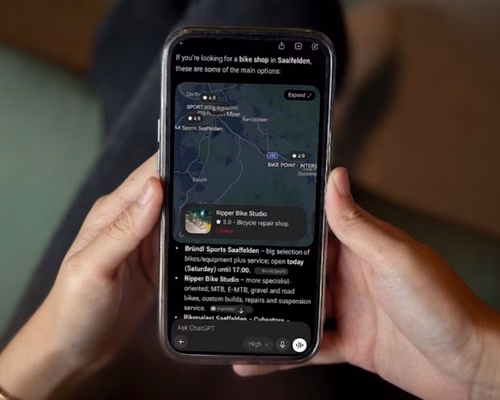 Nahaufnahme von Händen, die ein Smartphone halten, mit einer KI-Suche nach lokalen Fachbetrieben im modernen Mobile-Mockup von Lumios & Co